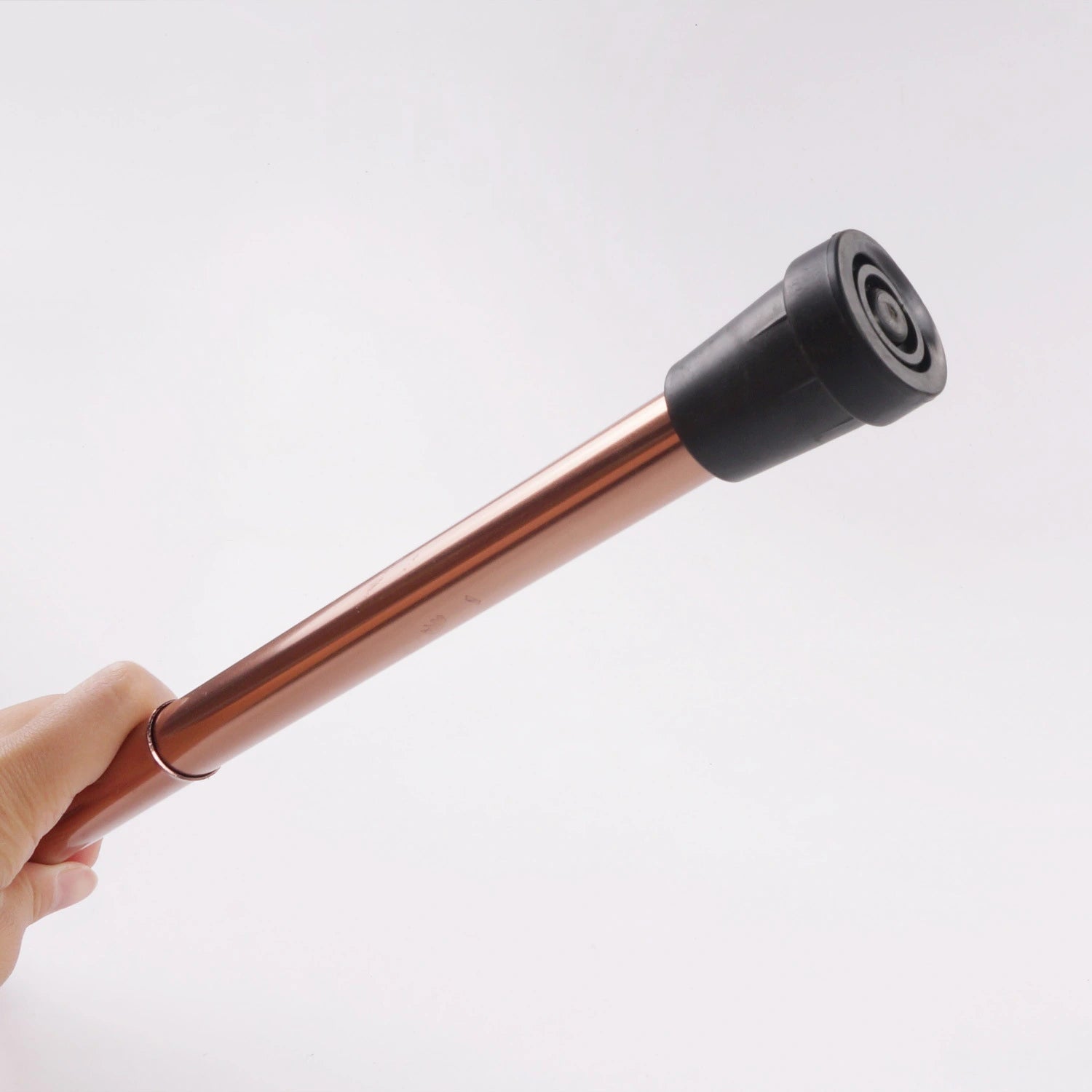  The shaft of the walking stick is a glossy copper color, offering a stylish aesthetic. This close-up view highlights the simplicity and functionality of the design, focusing on the practical aspect of the rubber tip which is essential for safe walking on various surfaces. This type of walking stick is ideal for individuals needing support and balance while walking, combining safety with an elegant appearance.